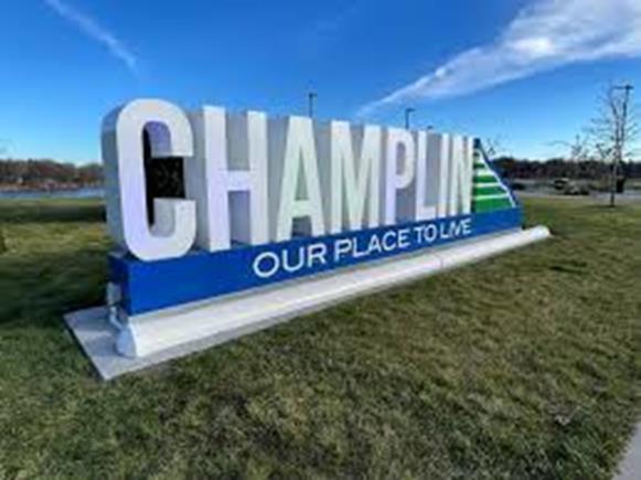 Champlin our place to live sign on grass with a blue sky background
