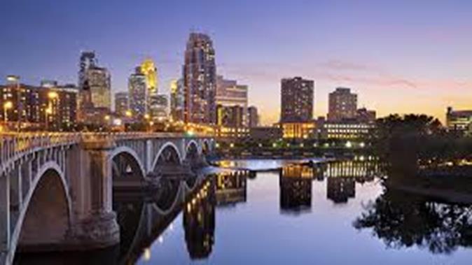 Image of city with a bridge over a body of water reflecting the city lights and buildings