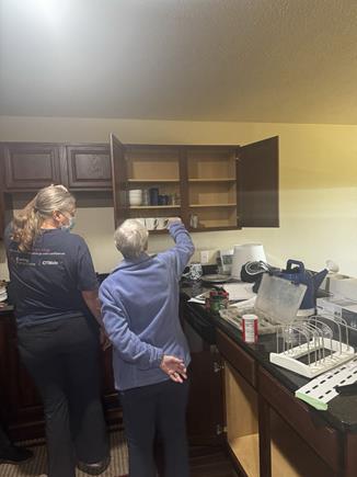 Caring Transitions team member assisting a senior in organizing and downsizing kitchen cabinets during a home transition in Maple Grove, MN.